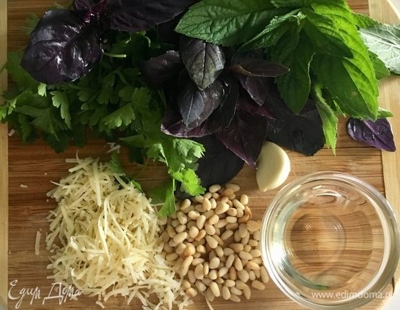 Сделаем соус песто для верха пирога. Для него берем по пучку базилика, петрушки и мяты. Зубчик чеснока. Горсть обжаренных кедровых орешков и немного натертого пармезана. Оливковое масло. Все ингредиенты взбить в блендере, посолить и поперчить немного.