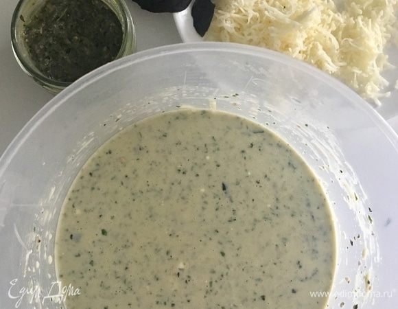 К яйцам и йогурту добавьте пару столовых ложек соуса песто, сыр фета, половину натертой моцареллы и снова перемешайте. Посолите по вкусу.