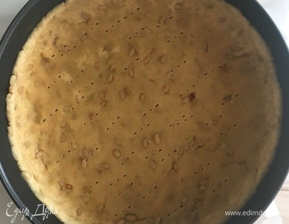 Берем разъемную форму (21 см), дно выстелить бумагой для выпечки, а бока смазать маслом. Распределить тесто в форме, формируя бортики. Сделать дырочки вилкой. Если есть время, уберите минут на 30 в холодильник. А после отправьте в разогретую до 180°C духовку на 20 мин