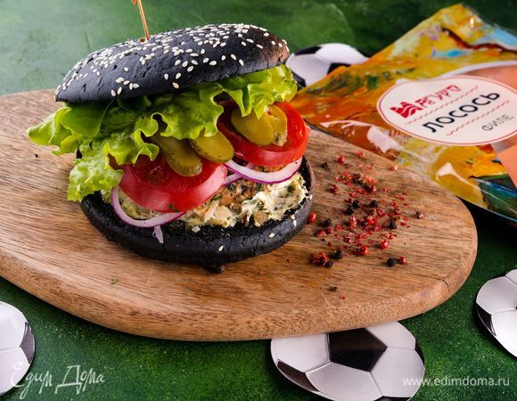Одну половинку булочки смажьте соусом, положите готовую котлету, кольца лука, кружочек помидора и салатный лист. Смажьте соусом вторую половинку булочки и накройте бургер. Сочный бургер для самых преданных фанатов фтубола готов!