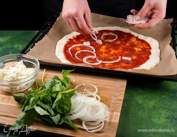 Противень застелите пергаментом. Положите заготовку из теста. Смажьте тесто томатным соусом.