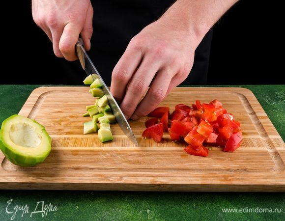 Помидор разрежьте на 4 части, очистите от семян. Нарежьте мелкими кубиками. Добавьте к измельченной смеси. Авокадо почистите, нарежьте кубиками.
