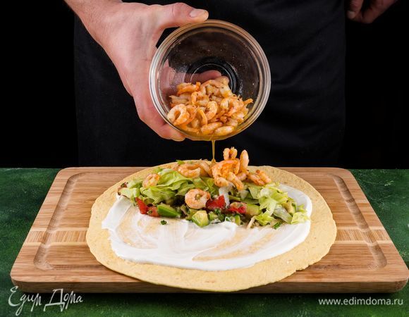 Добавьте в каждую по 1 столовой ложке сметаны, салат айсберг, сальсу и креветки.