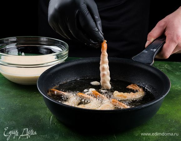 Берем креветку за хвостик и обмакиваем в кляр. На разогретую с растительным маслом сковороду выкладываем креветки.