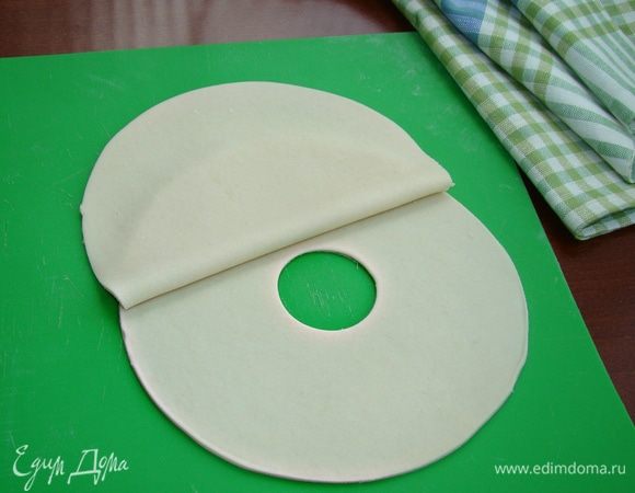 Достать тесто из холодильника и еще раз вымесить его. Затем сделать в виде колбаски и нарезать на одинаковые кусочки. Каждый кусочек раскатать в тонкую лепешку. На одно хинкали понадобится две лепешки. В середине одной лепешки выемкой сделать круглое отверстие. Накрыть сверху второй лепешкой, края слегка придавить.