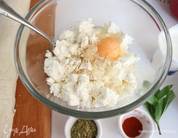 Чеснок очистить, выдавить через пресс в миску с тертым пармезаном, туда же добавить фетаксу, поломанную на кусочки, яйцо. Жидкость из упаковки с фетаксой сохранить для дальнейшего использования.