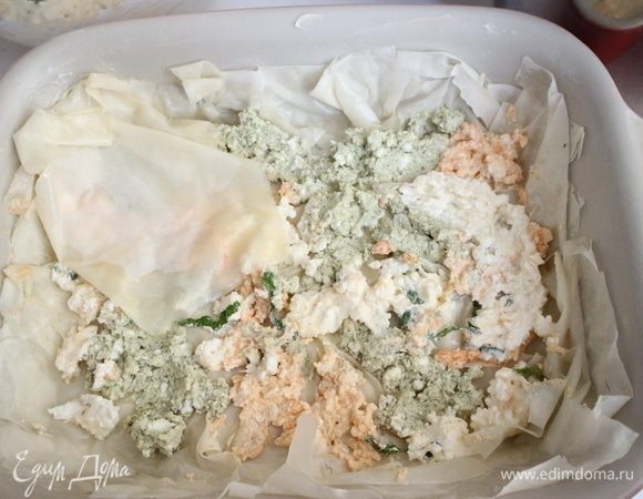 Продолжить таким же образом выкладывать слои, чередуя тесто фило, смоченное в жидкости с маслом, и сырную начинку из разных мисок.