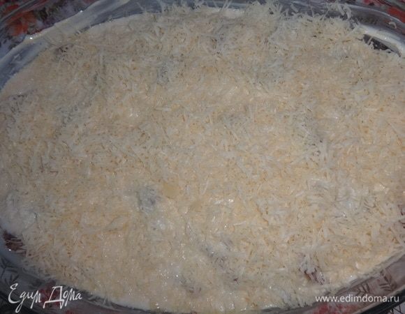 Поверх соуса насыпать слой тертого сыра.