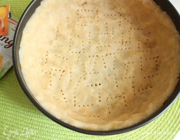 Духовку разогреть до 190°C. Достать тесто из холодильника, снять пленку, расправить тесто руками на донышке формы, сделать бортики из теста, наколоть дно из теста вилкой, убрать в холодильник. Через 15–20 минут вынуть форму из холодильника, отправить в духовку на 18 минут. Вынуть тесто в форме из духовки, дать немного остыть.