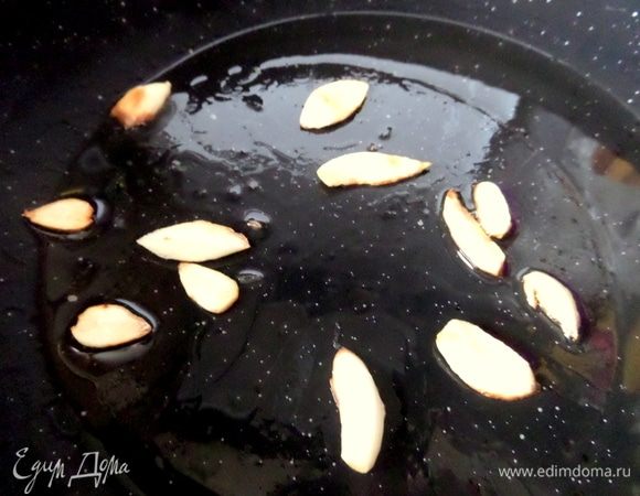 Чеснок нарезать слайсами и обжарить в воке на оливковом масле.