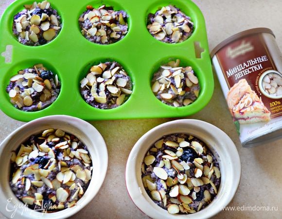 Формочки для маффинов смажьте маслом или вложите бумажные вкладыши. Разложите тесто по формочкам, сверху посыпьте лепестками миндаля, слегка окуная в тесто. Поставьте в разогретую до 180°C духовку и выпекайте в течение 40–45 мин.