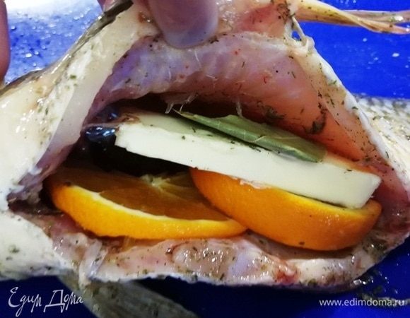 В брюшко кладем 2 кружочка апельсина, сливочное масло и лавровый лист.