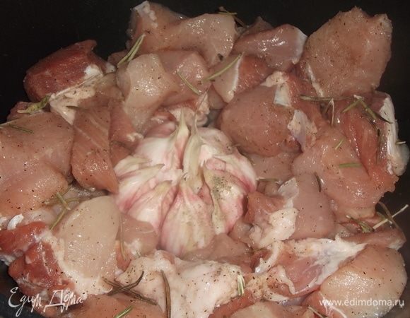 Свинину нарезать на крупные куски, посолить, поперчить. Выложить в посуду. С головки чеснока снять верхнюю шелуху, при этом оставляя головку целиком. Выложить в середину мяса, добавить розмарин.