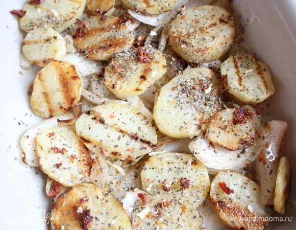 Разогреть сковороду-гриль с оливковым маслом, поместить лук и картофель, обжарить. Картофель должен быть не до конца прожаренным, оставаться чуть сыроватым. Форму смазать половиной из указанного количества сливочного масла. Духовку разогреть до 200°C. В форму поместить лук. Затем кружочки картофеля.