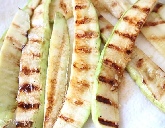 На сковороде-гриль с добавлением оливкового масла обжарить кусочки кабачка, уложенные на сковороду в один слой. Обжаренные кабачки положить на тарелку, застеленную бумажным полотенцем.