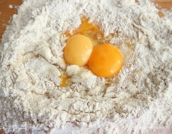 Сделать из муки «колодец» на рабочей поверхности, в центр поместить 2 яйца и 2 желтка, перемешать с помощью вилки. Добавить оливковое масло, перемешать руками.
