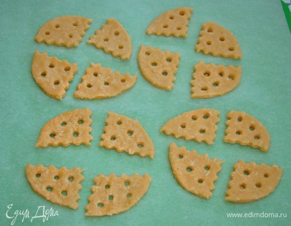 Часть теста раскатать в пласт толщиной примерно 0,5 см. Вырезать круг, затем круг разрезать на сегменты и с помощью коктейльной соломки сделать дырочки.