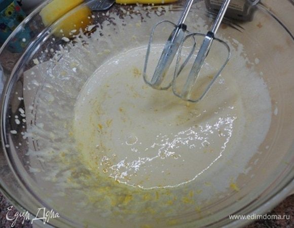 Начать лучше с подготовки формы для выпечки, чтобы готовое тесто не затягивалось после приготовления и ожидания, когда будет готова форма. Итак, разъемную форму диаметром 24 см смазываем сливочным маслом и посыпаем мукой. Излишки муки стряхиваем. Духовку включаем на прогрев до 170–180°C. Желтки отделяем от белков и взбиваем с сахаром до его полного растворения. Добавляем цедру половины лимона.