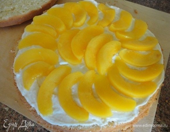 Для пропитки 50 мл сиропа от персиков смешайте с лимончелло и пропитайте бисквит, разрезанный на два коржа. Смажьте один корж половиной крема и выложите большую часть долек персиков.