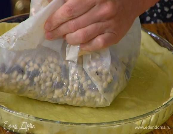 Форму смазать сливочным маслом, выложить тесто, сформировав бортики, сверху поместить бумагу для выпечки, насыпать любые бобовые и выпекать в разогретой духовке 15 минут.