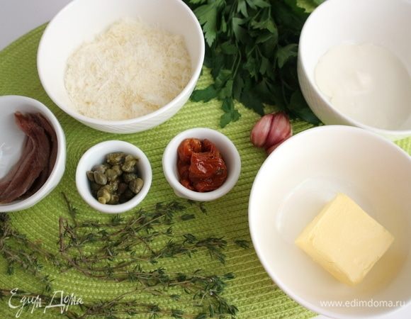 Приготовить все необходимое для начинки. Чеснок почистить. Сыр натереть на мелкой терке, вяленые томаты в масле нарезать на небольшие кусочки. К размягченному при комнатной температуре маслу добавить чеснок, пропущенный через пресс, белый свежемолотый перец, соль, перемешать вилкой.