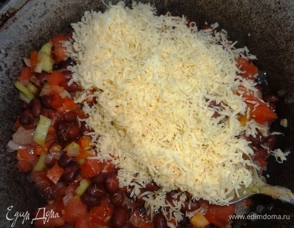 Отложить 1/4 часть сыра, остальной сыр выложить в сковороду с овощами и фасолью, перемешать.