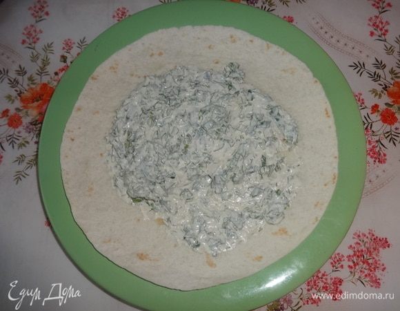 Теперь приступаем к сборке закуски. Круглую лепешку-тортилью смазать посередине небольшим количеством сметанного соуса.