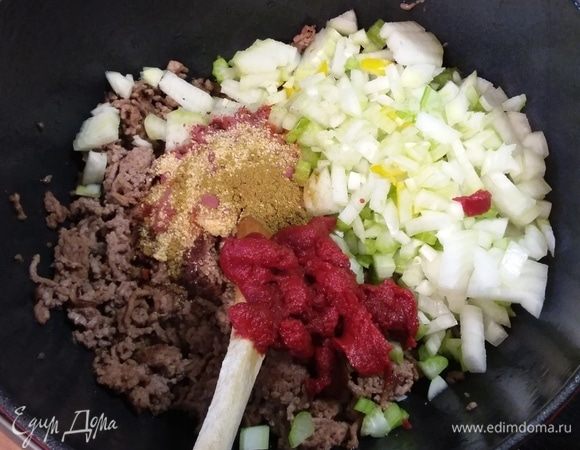 Через 5 минут добавить лук, сельдерей, специи и томатную пасту и обжарить вместе в течение еще нескольких минут.