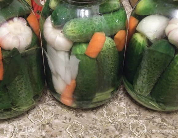 Заполнить банки огурцами и доложить чеснок, морковь и лук.