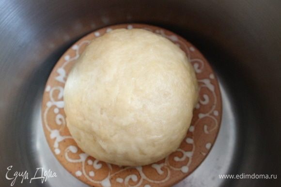В большой теплоемкой кастрюле вскипятить воду. Вылить воду, на дно горячей сухой кастрюли поставить керамическое блюдце, на него положить тесто, закрыть крышкой кастрюлю и оставить на 30 минут. Можно просто накрыть тесто горячей кастрюлей.