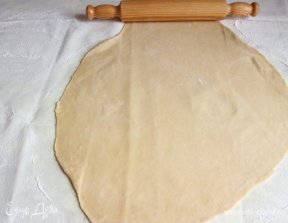 Немного раскатать тесто скалкой от центра к краям.