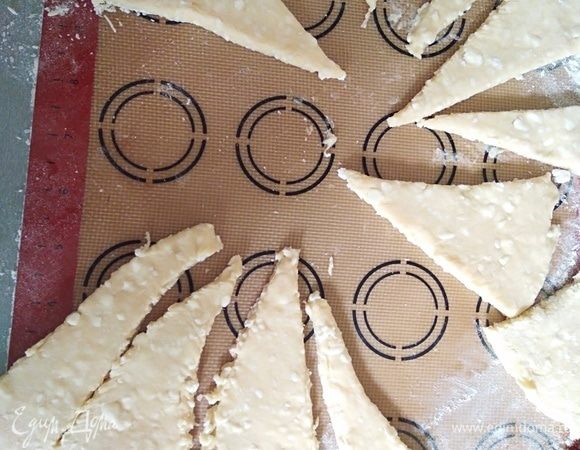 Ввести муку и соду. Замесить мягкое, но не липкое тесто. Количество муки может понадобиться больше или меньше на 50 грамм, зависит от жирности и влажности творога. Убрать в холодильник на 20 минут. Разделить на 2 части. Раскатать в круг, нарезать на сегменты.