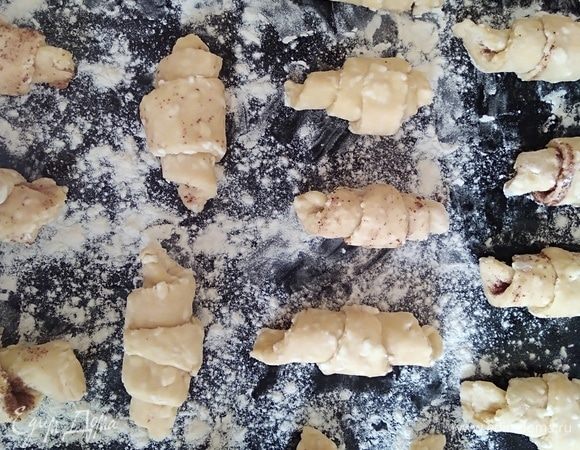 Скрутить рогалики, начиная с толстого края сегмента. Можно по вкусу присыпать сначала сладким какао или ванильным сахаром. Поместить на противень, посыпанный мукой.