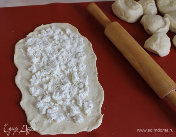 Тесто готово, начинка тоже, формируем лодочки. Разделите тесто на кусочки размером с женский кулачок, подкатайте каждый в шар. Раскатайте каждый шарик в овал толщиной 5 мм. Разложите немного начинки по всей поверхности подготовленной лепешки. По краям начинки положите немного, размажьте ее по поверхности, а в середине, конечно, ее должно быть больше.