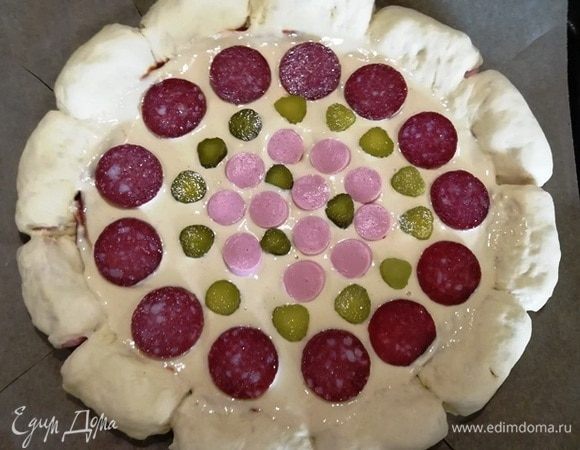 По кругу выкладываем сырокопченую колбасу, маринованный огурчик, сосиску.