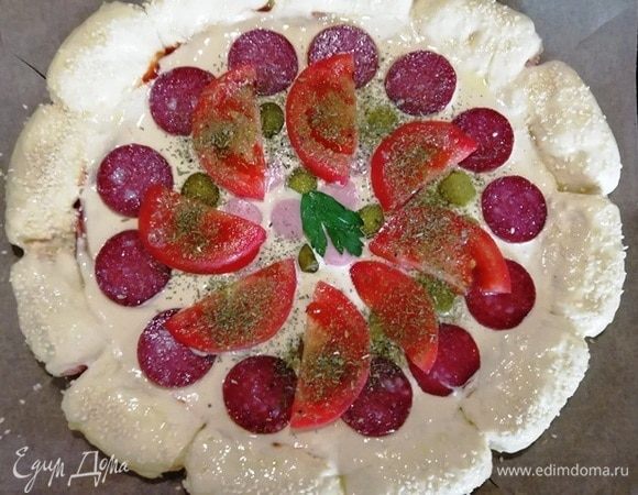 Следом выкладываем помидор, посыпаем прованскими травами. Края пиццы я смазала взбитым яйцом и посыпала кунжутом. Это по желанию.