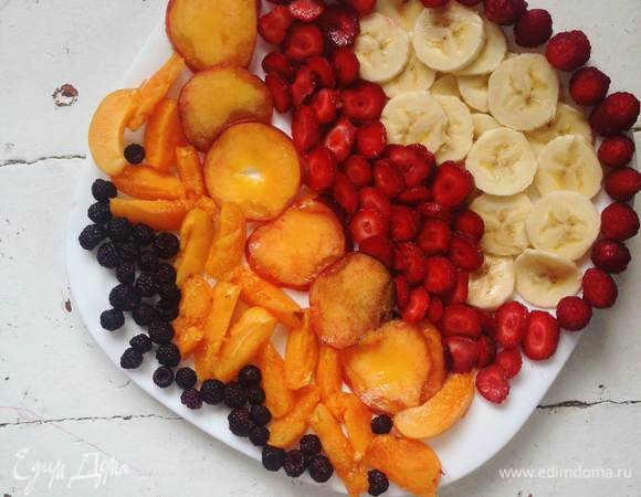 Смазываем форму маслом, кладем шарик теста на дно и раскатываем пальцами, формируя бортики по бокам и «тарелочку» посередине. Смазываем дно «тарелки» ряженкой или жирными сливками. Выкладываем фрукты и ягоды, ставим в разогретую до 200°C духовку.