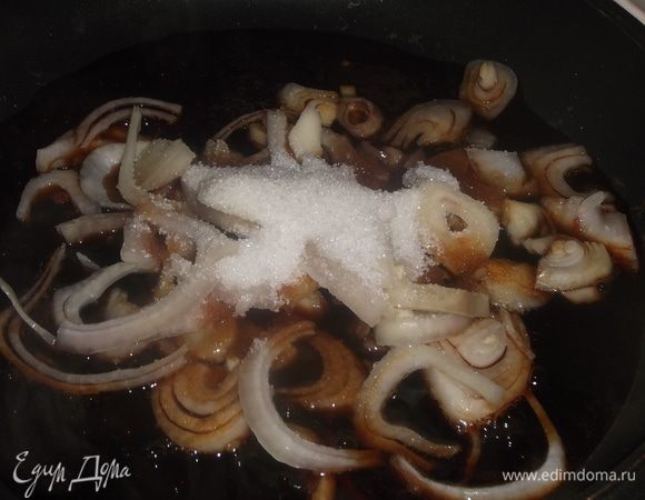 В сковороду налить соевый соус. Довести до кипения и добавить нарезанный полукольцами лук. Посыпать сахаром. Обжаривать, помешивая, 3 минуты.