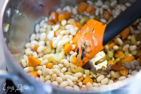 К овощам добавить фасоль, влить бульон и довести до кипения. Затем добавить мелконашинкованную капусту, довести до кипения, дать покипеть 2–3 минуты и отправить кастрюлю с супом в духовку (200°C) на 15 минут.