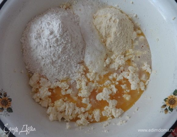 Соединить вместе взбитые яйца и масляно-творожную массу. Всыпать оба вида муки, предварительно просеянных. Положить гашеную уксусом соду.