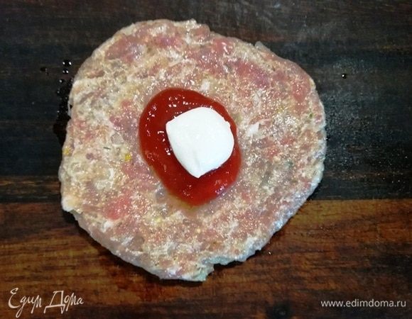 Делим фарш на одинаковые круглые заготовки. У меня получилось 10 штук. Аккуратно придавливаем шарик фарша. В центр заготовки кладем немного кетчупа и маленький шарик моцареллы (или другого сыра).