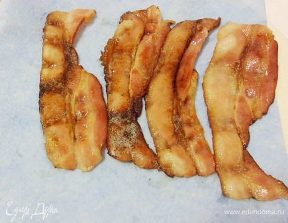 Затем переложить полоски обжаренного бекона со сковороды на бумажную салфетку для удаления лишнего жира.