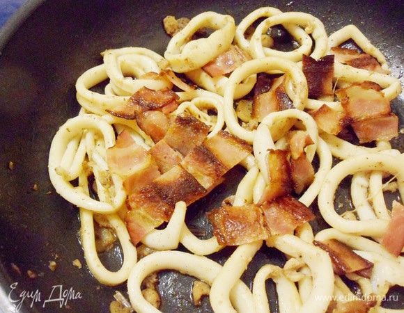 Вернуть ломтики бекона к кальмарам на сковороду, перемешать. Все, блюдо готово!
