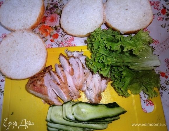 Булочки разрезать вдоль пополам. У меня булочки с кунжутом. Листья салата вымыть, обсушить. Куриную грудку (у меня жареная) нарезать тонкими ломтиками поперек волокон. Огурцы вымыть, обсушить, нарезать вдоль тонкими пластинами.