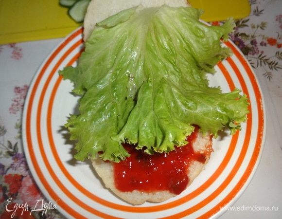 Начинаем собирать бургер. Нижнюю часть булочки смазать 1/2 ст. л. кетчупа и положить салатный лист.