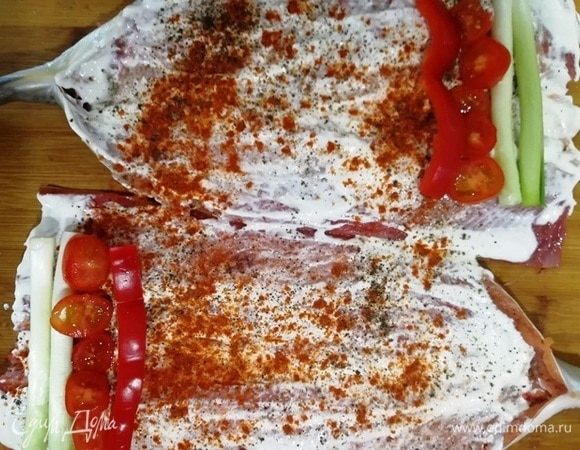 Смазываем филе сметаной. Выкладываем белые части зеленого лука, помидоры и болгарский перец.
