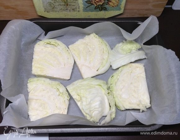 На противень — пергамент, капусту толсто нарезанными пластами на дно уложили.