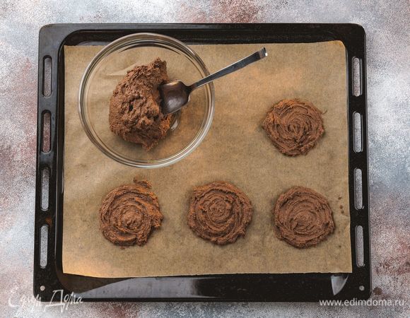 Противень застелите бумагой для выпечки. Ложкой выложите порционно заготовки печенья. Выпекайте при 180°С 15–20 минут.<br />
 