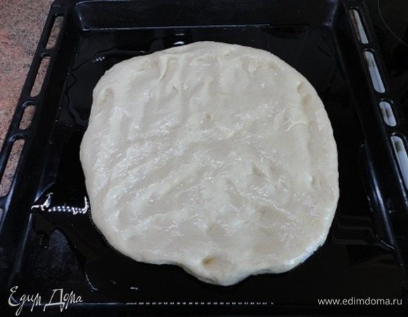 Оставшееся масло распределите по противню, обваляйте в нем тесто и с помощью рук придайте ему примерно такую форму. Накройте полотенцем и оставьте на 3 часа.