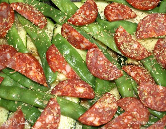 Выкладываем цукини в жаропрочную форму. На цукини выкладываем отваренную фасоль, чоризо. Посыпаем орегано.